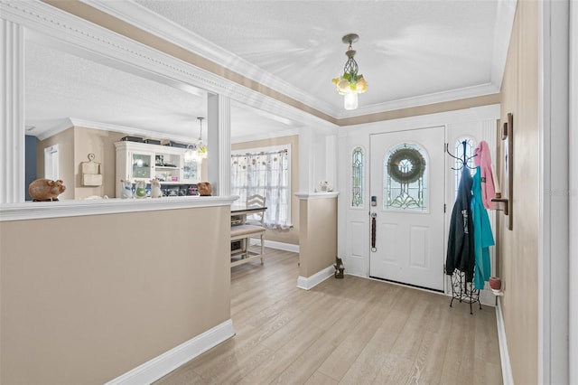 foyer featuring light wood-type flooring, crown molding, and a textured ceiling