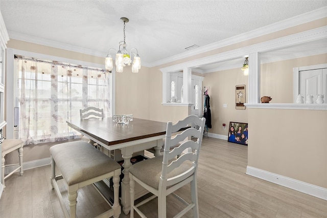 dining room with light wood-type flooring, a notable chandelier, a textured ceiling, and ornamental molding