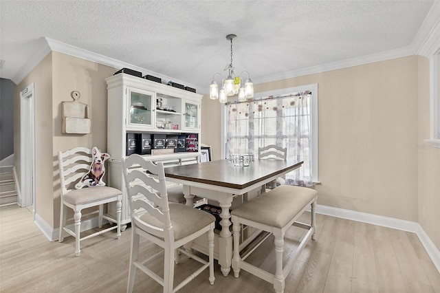 dining room with a textured ceiling, ornamental molding, a chandelier, and light hardwood / wood-style flooring