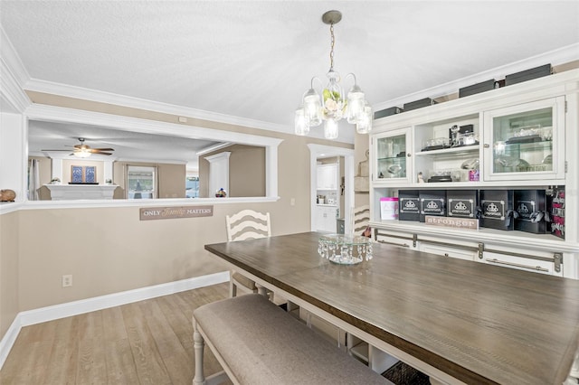 dining space featuring a textured ceiling, crown molding, ceiling fan with notable chandelier, and hardwood / wood-style flooring