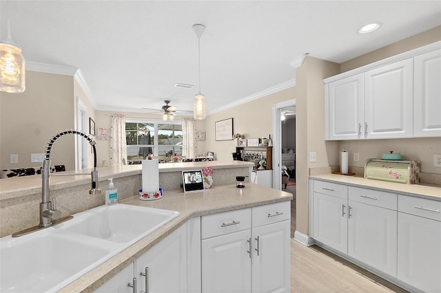 kitchen with ceiling fan, white cabinets, hanging light fixtures, and sink