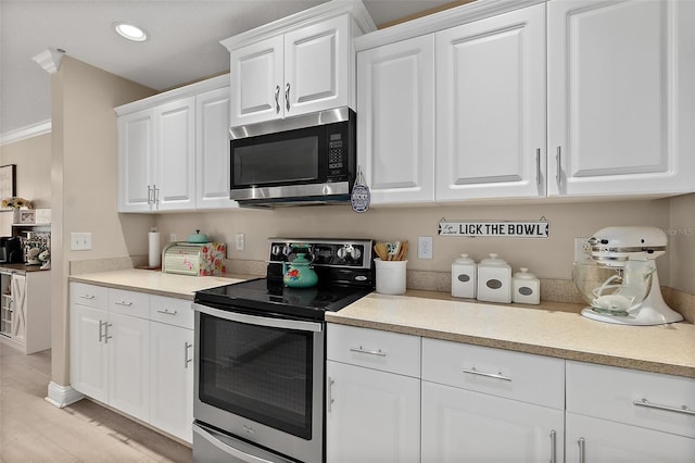 kitchen with white cabinets, light wood-type flooring, and stainless steel appliances