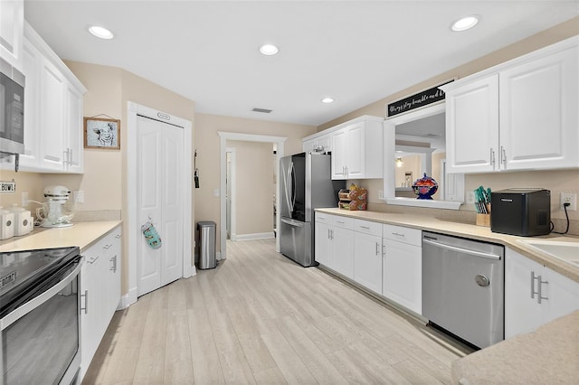 kitchen featuring white cabinets, light wood-type flooring, and stainless steel appliances