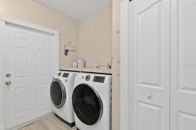 washroom featuring independent washer and dryer, a textured ceiling, and light hardwood / wood-style floors