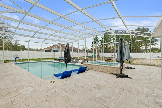 view of pool with a patio, glass enclosure, and an in ground hot tub