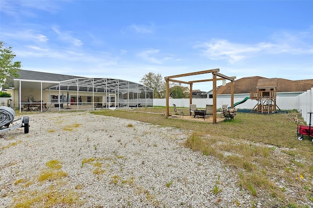 view of yard with a lanai, an outdoor fire pit, and a playground