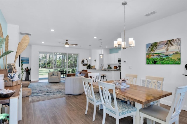 dining space with sink, ceiling fan with notable chandelier, and light hardwood / wood-style flooring