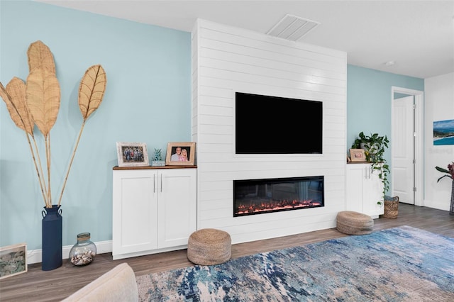 living room with dark hardwood / wood-style floors and a large fireplace