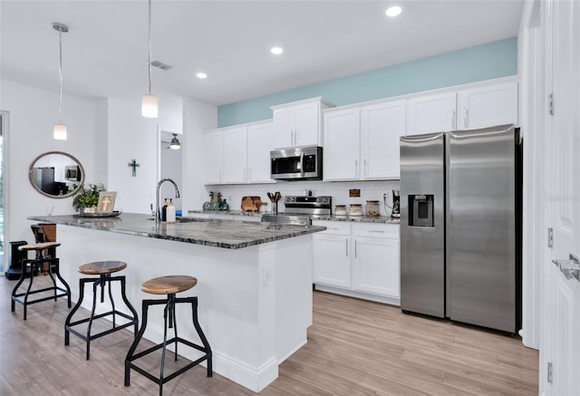 kitchen featuring an island with sink, appliances with stainless steel finishes, sink, and white cabinets