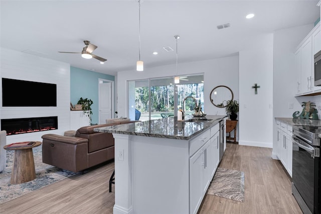 kitchen featuring sink, hanging light fixtures, dark stone counters, stainless steel appliances, and white cabinets