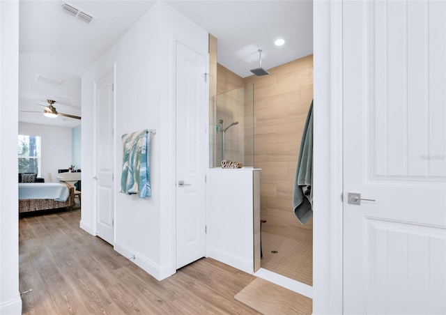 bathroom featuring ceiling fan, wood-type flooring, and tiled shower