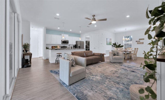 living room featuring ceiling fan and light hardwood / wood-style flooring