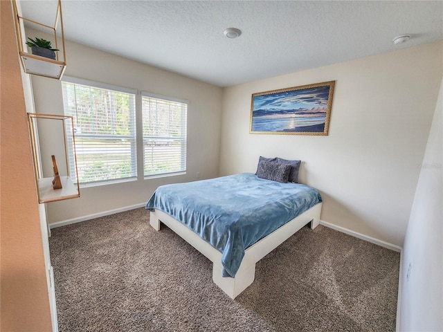 bedroom with dark carpet and a textured ceiling