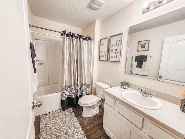 full bathroom featuring toilet, shower / bath combo, wood-type flooring, a textured ceiling, and vanity