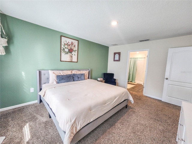 carpeted bedroom featuring a textured ceiling and ensuite bath