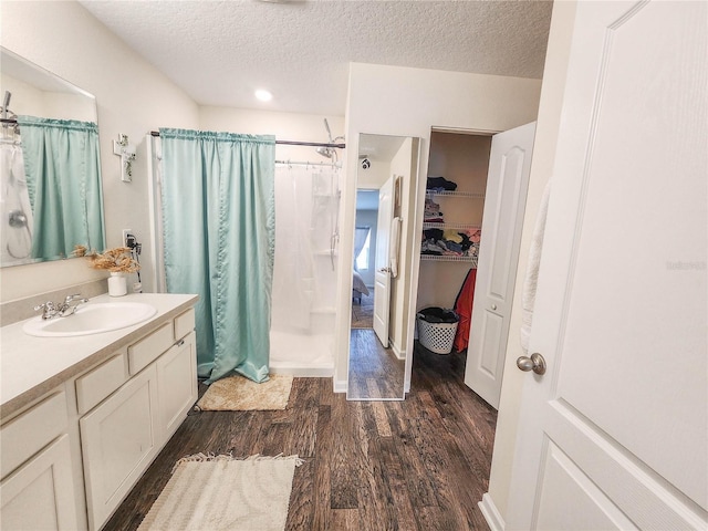 bathroom featuring curtained shower, wood-type flooring, vanity, and a textured ceiling