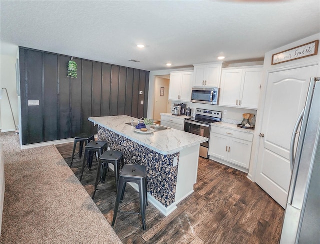 kitchen with a breakfast bar area, appliances with stainless steel finishes, white cabinetry, and a center island