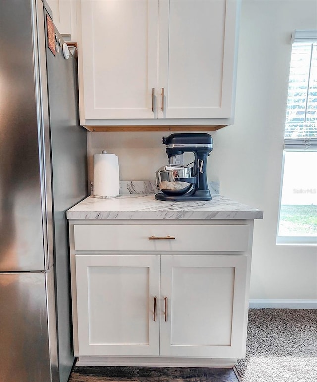 bar featuring white cabinetry, stainless steel fridge, and a wealth of natural light