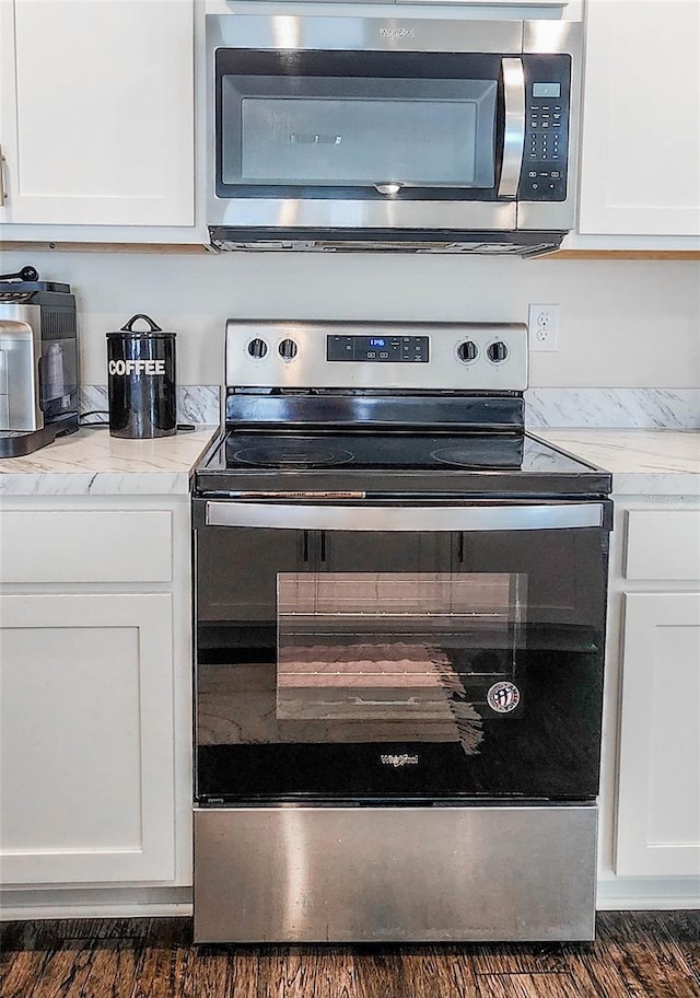 interior details with light stone counters, white cabinets, dark hardwood / wood-style floors, and stainless steel appliances