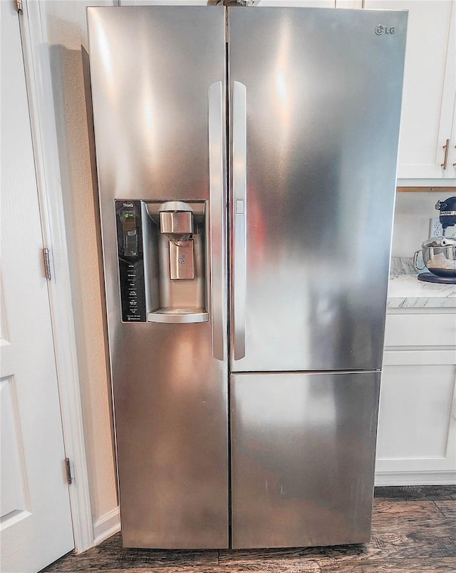 room details with stainless steel refrigerator with ice dispenser, dark hardwood / wood-style flooring, white cabinets, and light stone counters