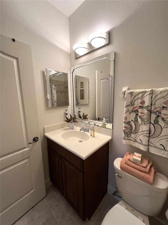 bathroom with tile patterned flooring, vanity, and toilet