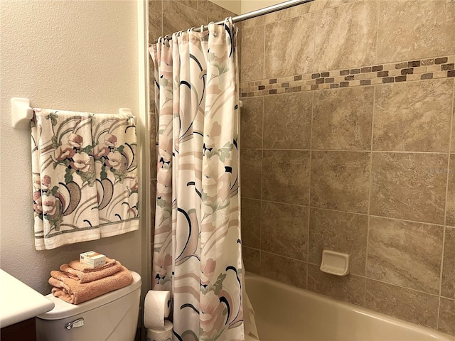 bathroom featuring a textured wall, shower / bathtub combination with curtain, and toilet