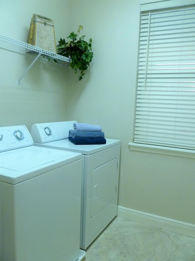 clothes washing area featuring laundry area, baseboards, and washer and dryer