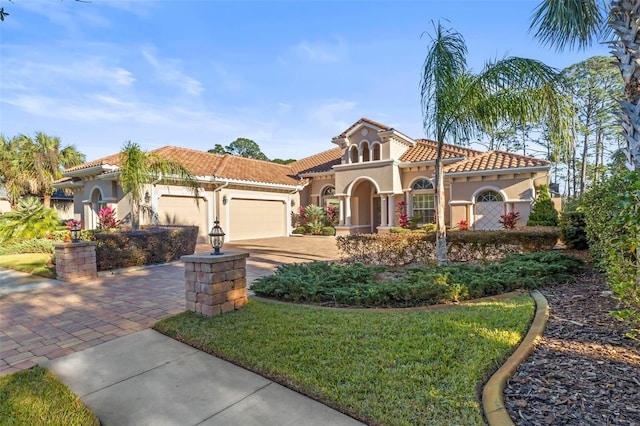 mediterranean / spanish-style house featuring a garage and a front lawn