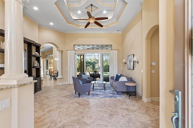 living room with ceiling fan, a towering ceiling, ornamental molding, and ornate columns