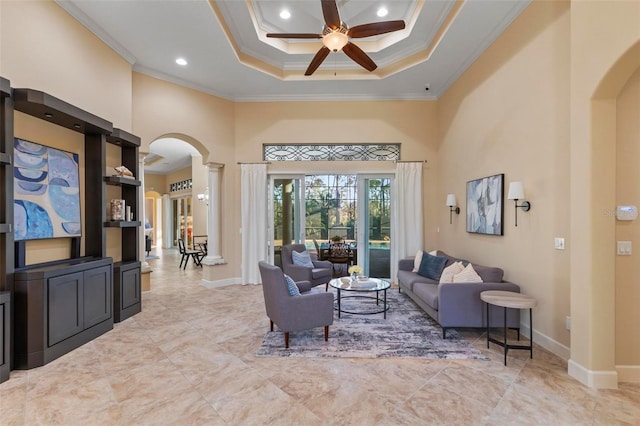 living room featuring ceiling fan, ornamental molding, and a high ceiling