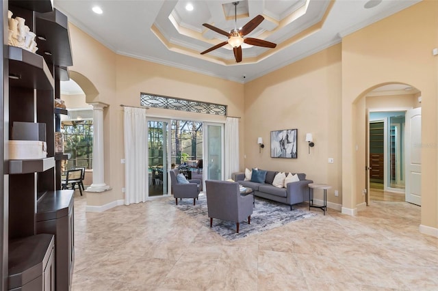 living room featuring ceiling fan, a high ceiling, decorative columns, and crown molding