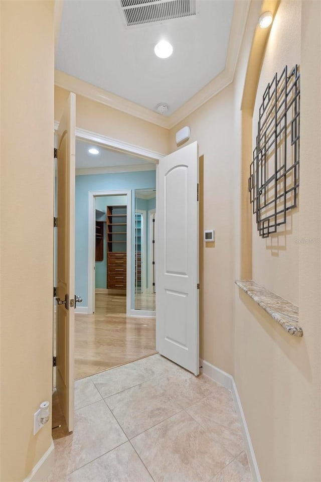 hall featuring light tile patterned floors and crown molding