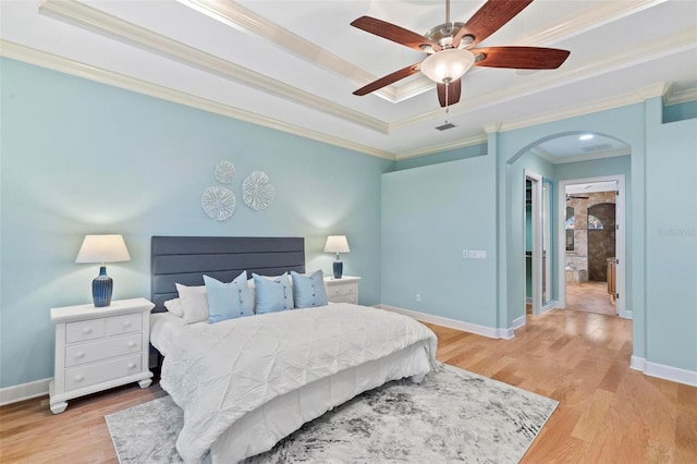 bedroom with ceiling fan, ensuite bath, light wood-type flooring, ornamental molding, and a closet