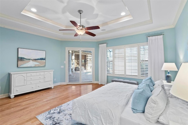 bedroom with ceiling fan, a tray ceiling, light hardwood / wood-style flooring, and ornamental molding