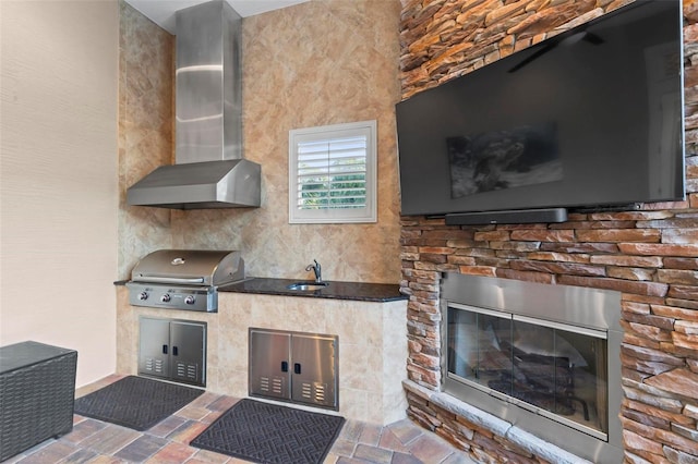 view of patio with grilling area, an outdoor kitchen, a fireplace, and sink