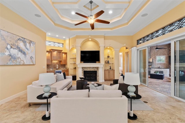 living room with ceiling fan, a high end fireplace, ornamental molding, and a towering ceiling