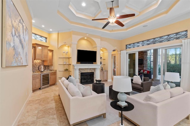 living room featuring a fireplace, ceiling fan, crown molding, and wine cooler