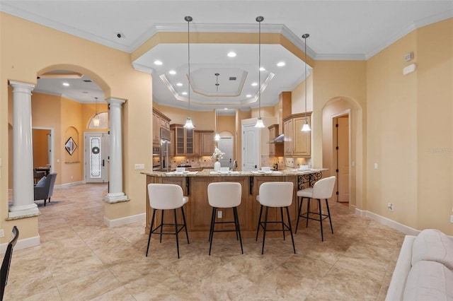 kitchen with light stone counters, ornamental molding, and pendant lighting