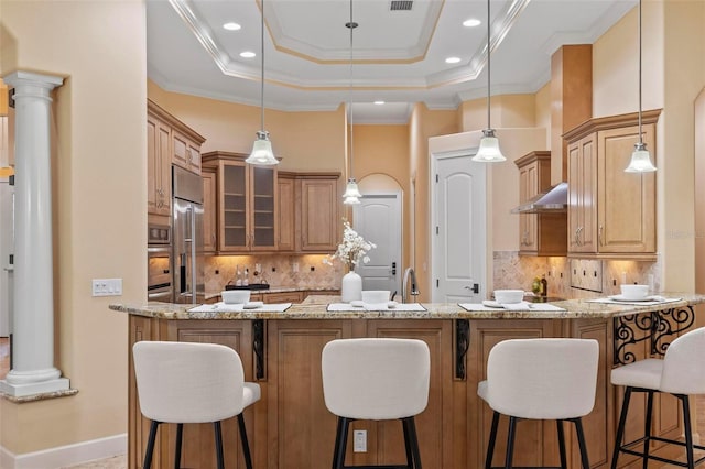 kitchen featuring ornate columns, decorative backsplash, light stone counters, and decorative light fixtures