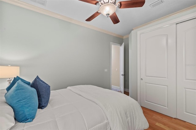 bedroom with ceiling fan, a closet, crown molding, and light hardwood / wood-style flooring