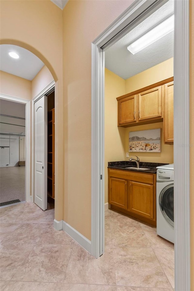 kitchen featuring washer / dryer, dark stone countertops, and sink