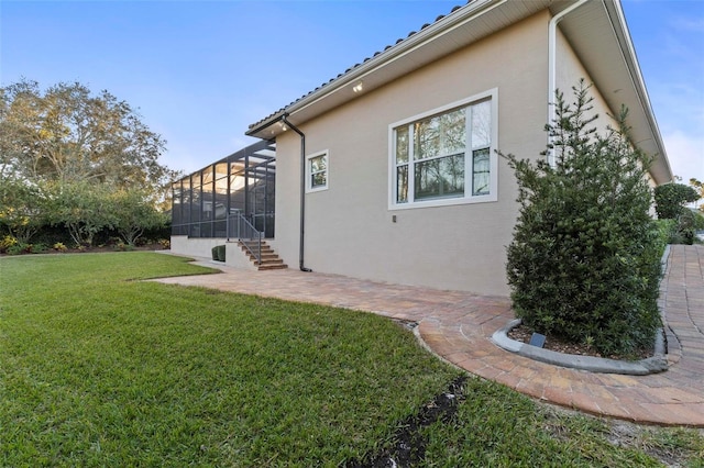 back of property with glass enclosure, a patio area, and a lawn