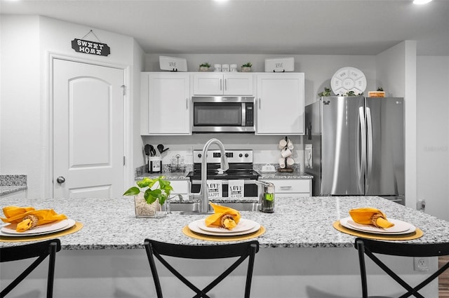 kitchen with breakfast area, appliances with stainless steel finishes, a kitchen bar, and white cabinetry