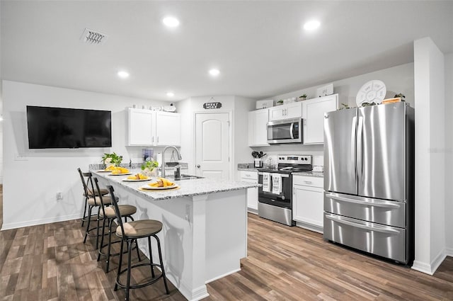 kitchen with a breakfast bar area, stainless steel appliances, white cabinetry, and sink