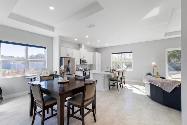 dining space featuring sink and a raised ceiling