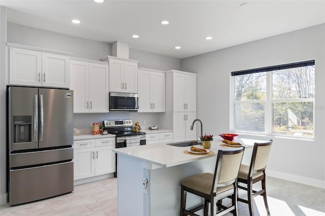 kitchen with stainless steel appliances, sink, a center island with sink, and white cabinets