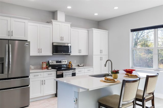 kitchen with a breakfast bar, sink, a center island with sink, stainless steel appliances, and white cabinets