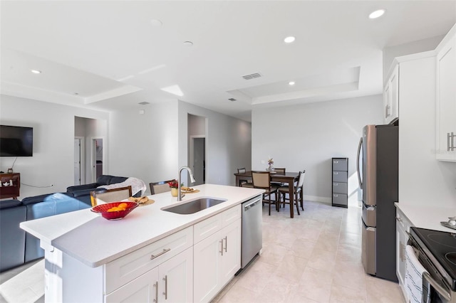 kitchen featuring sink, a center island with sink, appliances with stainless steel finishes, a raised ceiling, and white cabinets