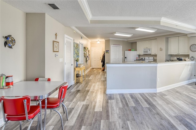 kitchen featuring white appliances, a textured ceiling, light hardwood / wood-style floors, kitchen peninsula, and ornamental molding