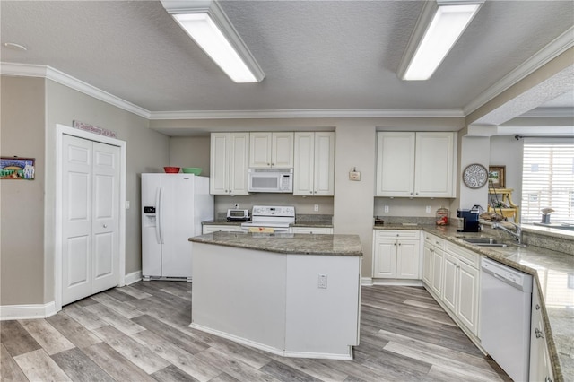 kitchen featuring a center island, white appliances, white cabinets, light stone counters, and sink